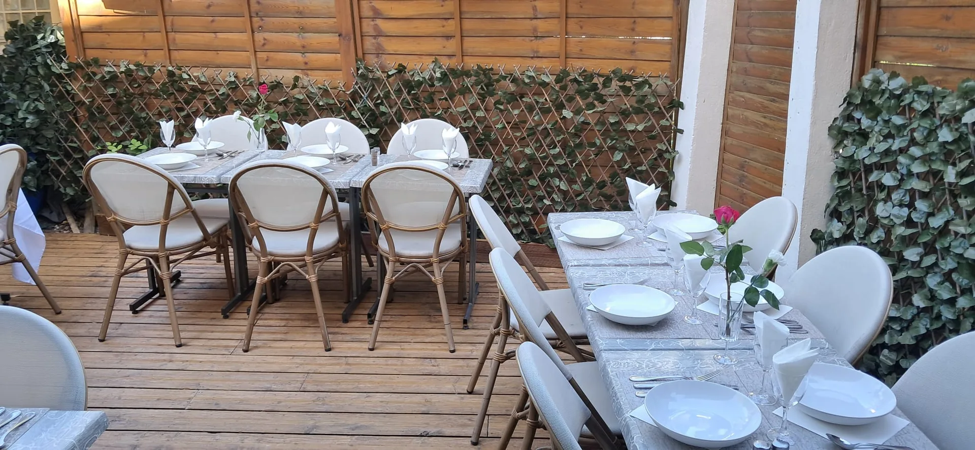 Tables dressées sur la terrasse en bois de La Source, entourées de verdure